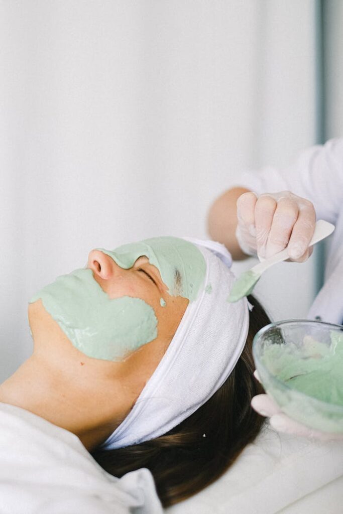 pexels-photo-5069459 Close-up of a woman receiving a green facial mask at a spa for skin rejuvenation.